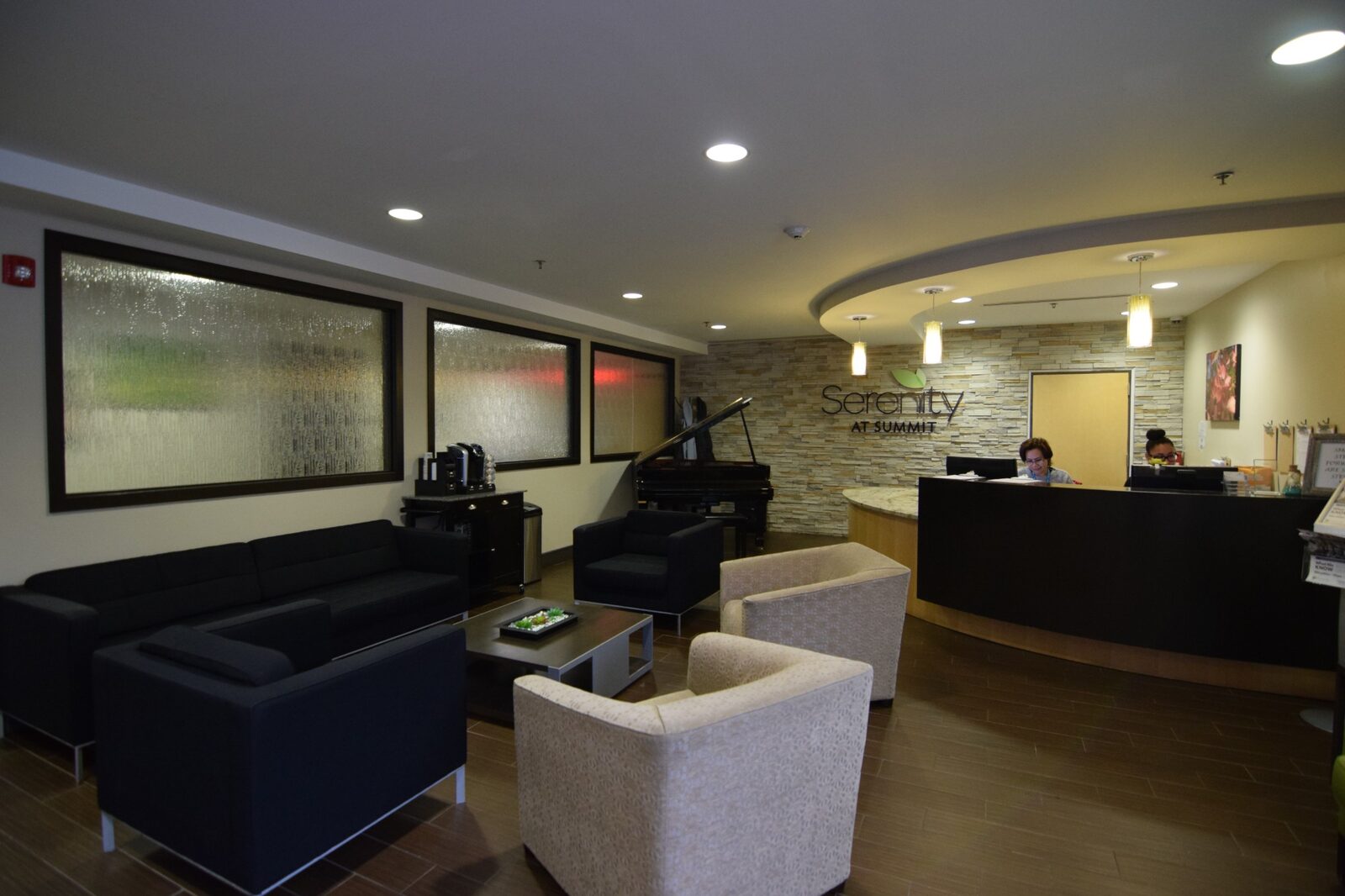 Reception desk with the Serenity at Summit sign, a piano and lounge seating