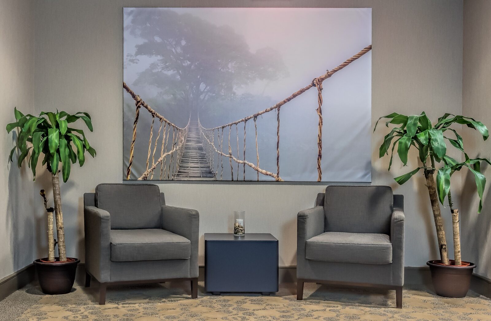 Two armchairs, a side table and a canvas of a rope bridge